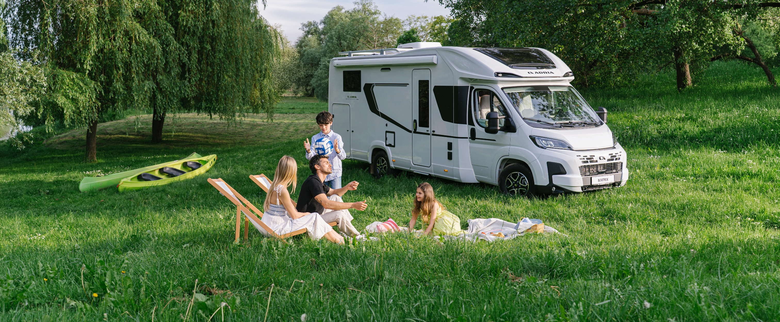 Eine Familie beim Camping mit dem ADRIA MATRIX Wohnmobil mit Hubbett vorne.