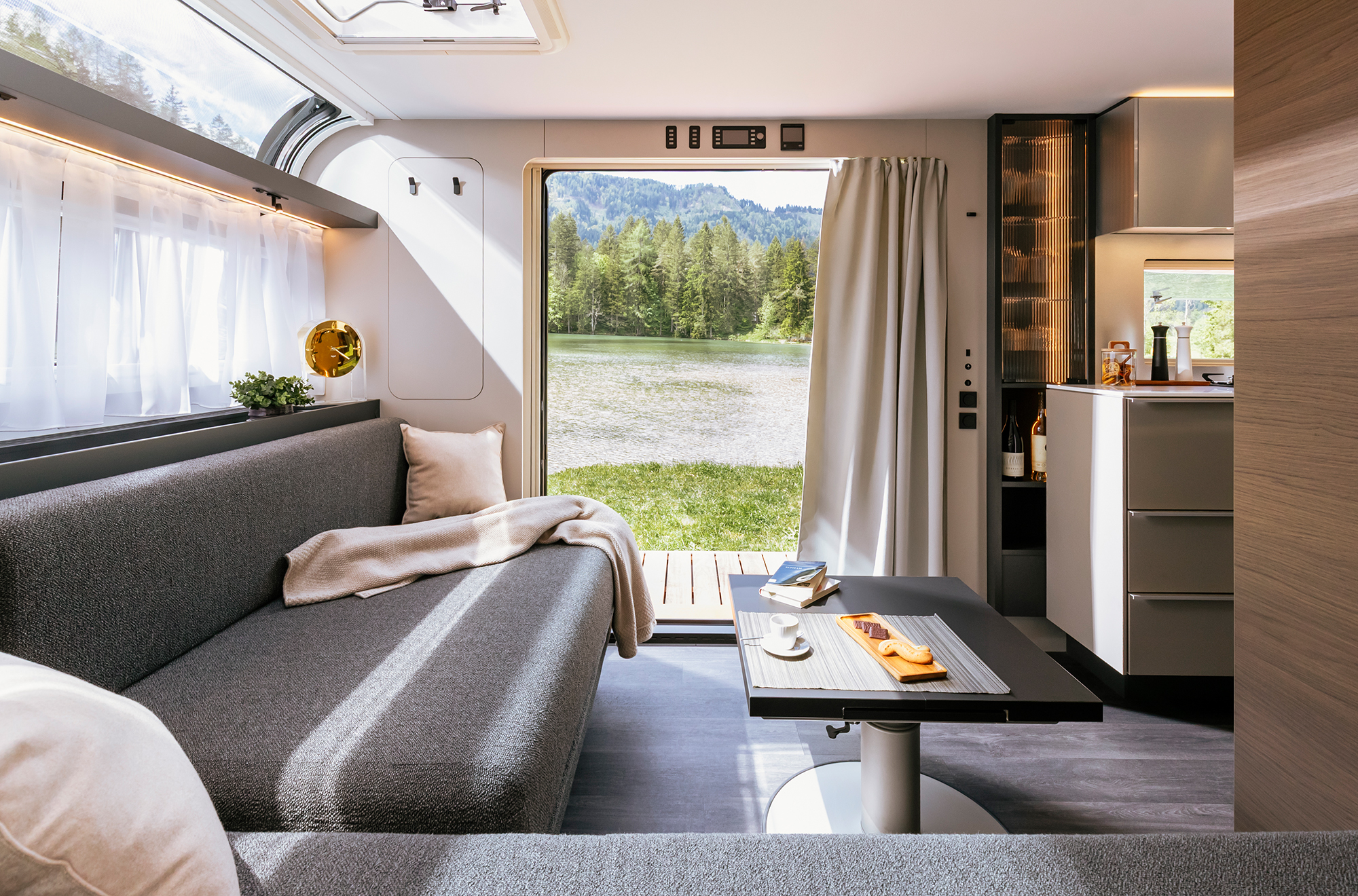 Die Panoramatüren im Luxus Wohnwagen ADRIA ASTELLA 754 DP sind offen und die Aussicht auf den Fluß und die Landschaft ist fantastisch.
