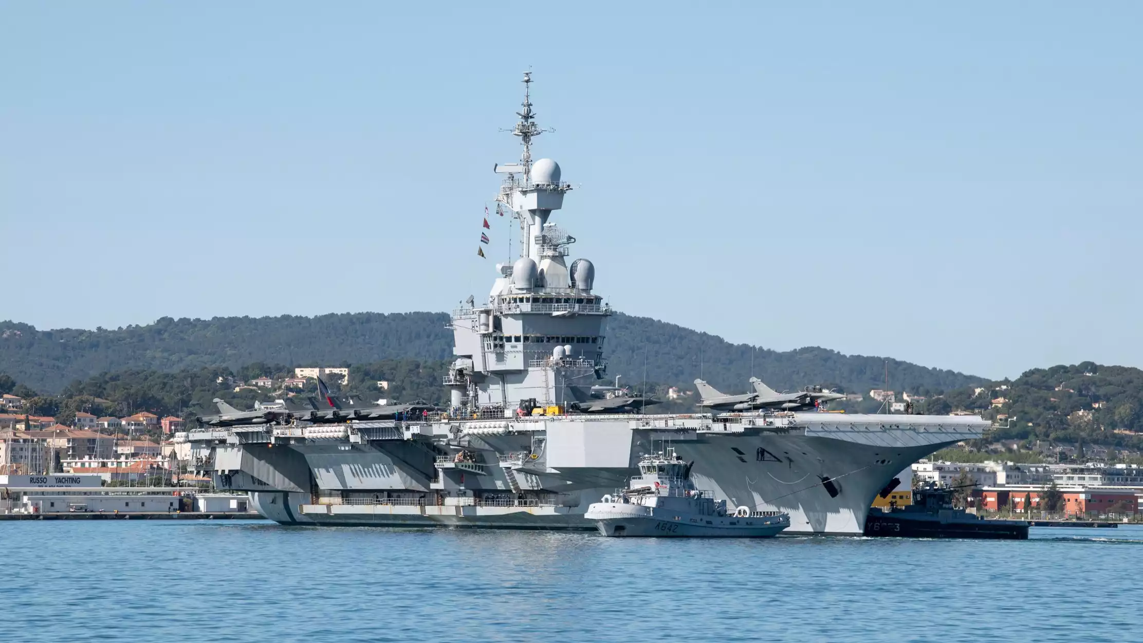 Appareillage du porte-avions Charles de Gaulle depuis Toulon pour la mission Akila (23 avril 2024). Des Rafale M et un E-2C Hawkeye sont visibles sur le pont d'envol.