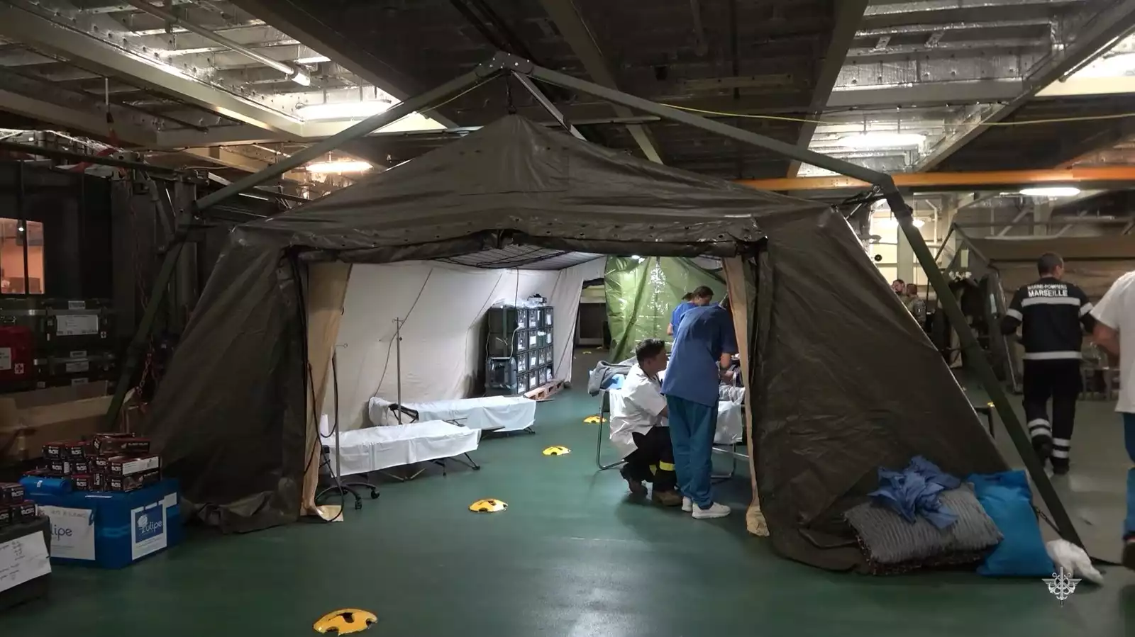 Hangar à véhicule du PHA Dixmude en partie reconditionné avec des tentes médicalisées et du matériel médical.