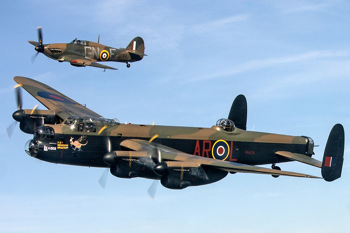 Bombardier Lancaster accompagné d'un chasseur Hurricanes. On aperçoit les marquages de bombes, cônes de glâce et coquelicots sur le nez de l'appareil.