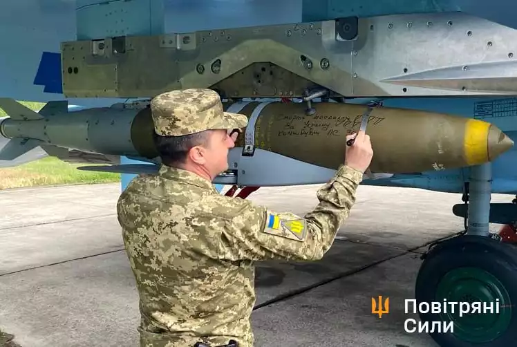 Le lieutenant général Mykola Oleshchuk, commandant la Force aérienne ukrainienne, signant une bombe planante JDAM-ER fixée sur un Su-27 Flanker.