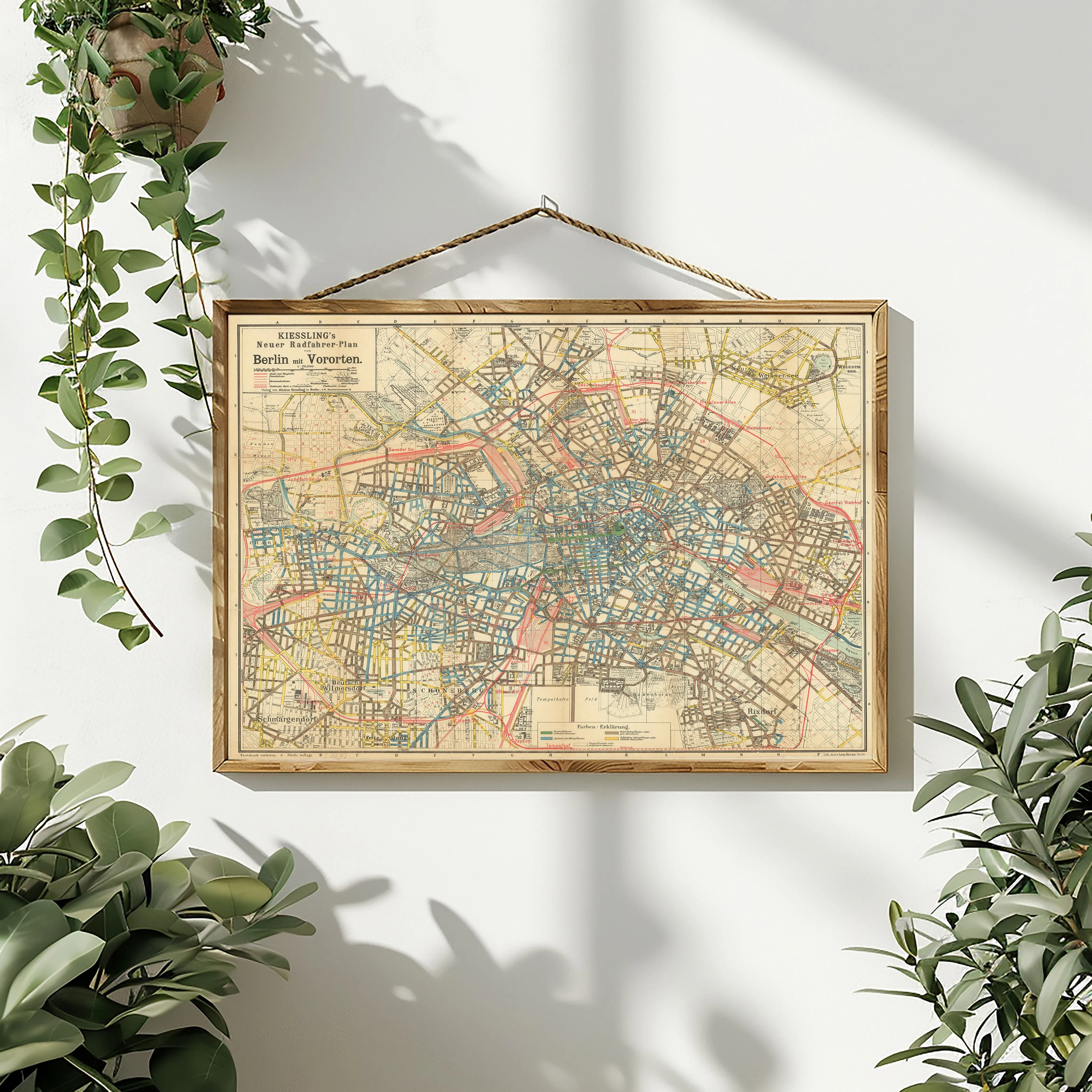 A framed map print hanging on a wall above a potted plant, with abstract decoration.