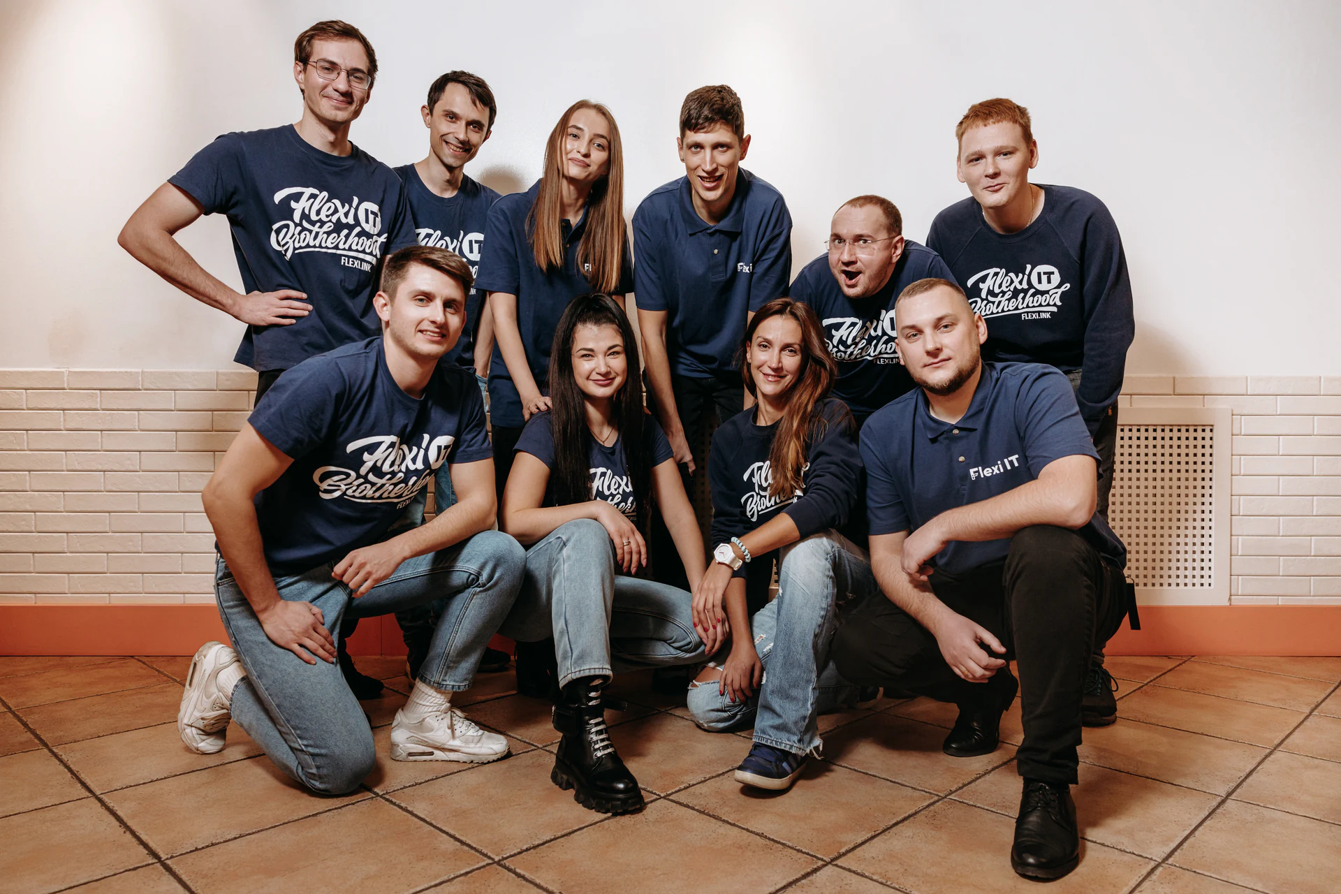 Ten Flexi IT team members in matching navy T-shirts against a white brick wall