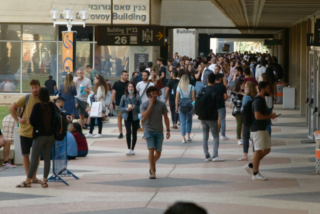 Large crowd of people walking through a busy outdoor corridor.