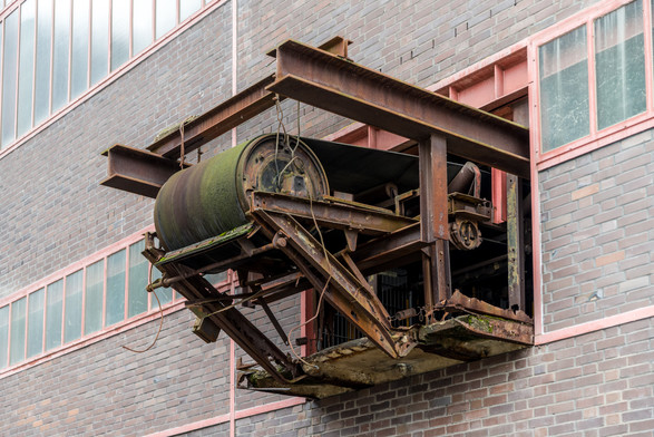 A former conveyor belt attachment protrudes from a building and looks as if it has broken through a window.