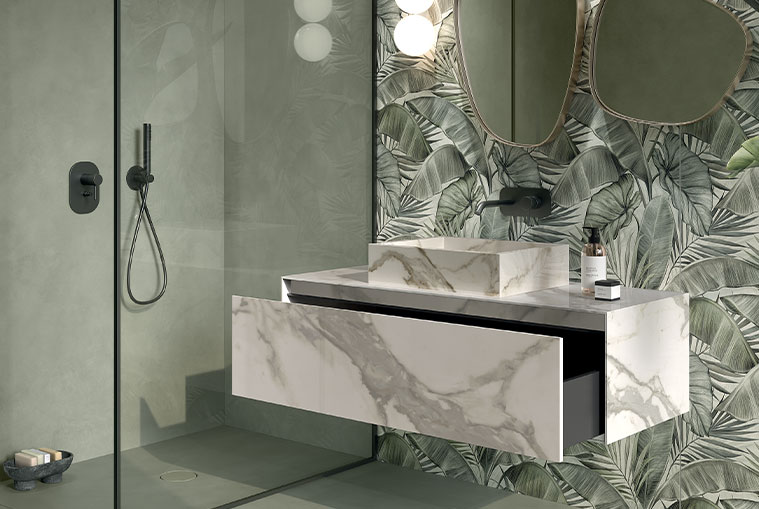 Wall-mounted bathroom vanity in white veined marble-effect stoneware, integrated sink, and wall with green tropical wallpaper.