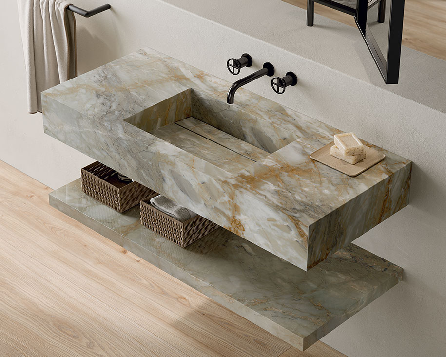 Wall-mounted onyx-effect stoneware sink with gold and gray veins, matte black faucets, and a matching countertop.