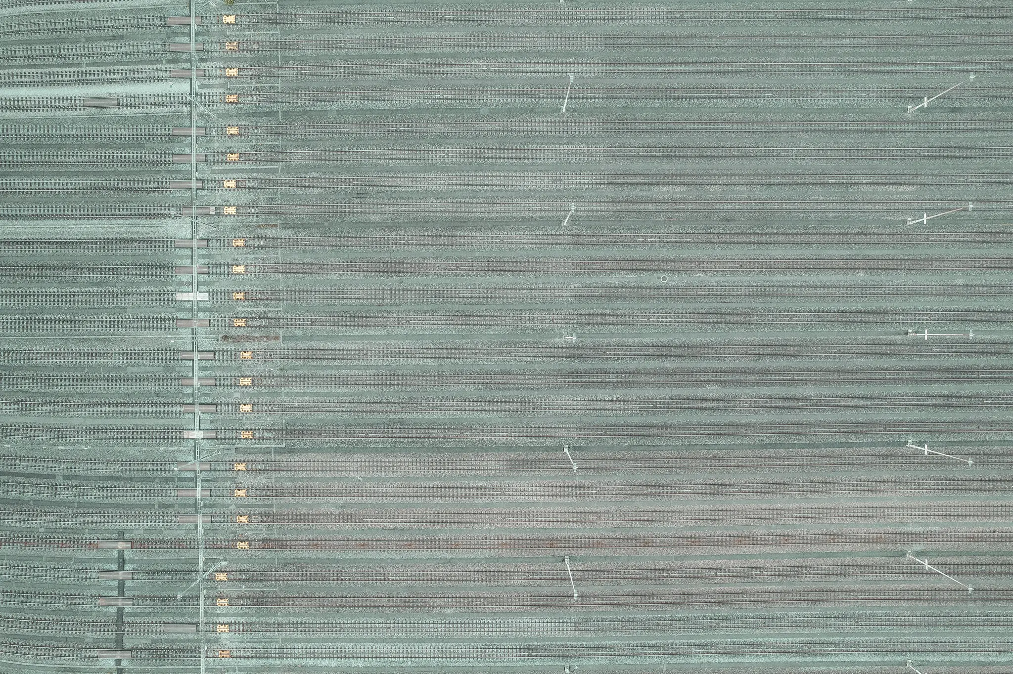 Una vista cenital de un extenso patio de maniobras con docenas de vías paralelas cubiertas por una fina capa de nieve o