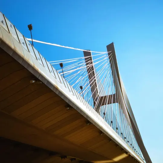 Toma de un puente atirantado desde un ángulo bajo. La parte inferior de la calzada del puente es marrón, con barandillas