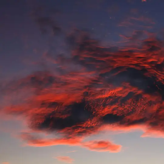 Un cielo dramático al atardecer o amanecer, con nubes oscuras intensamente iluminadas con vibrantes rojos y naranjas contra