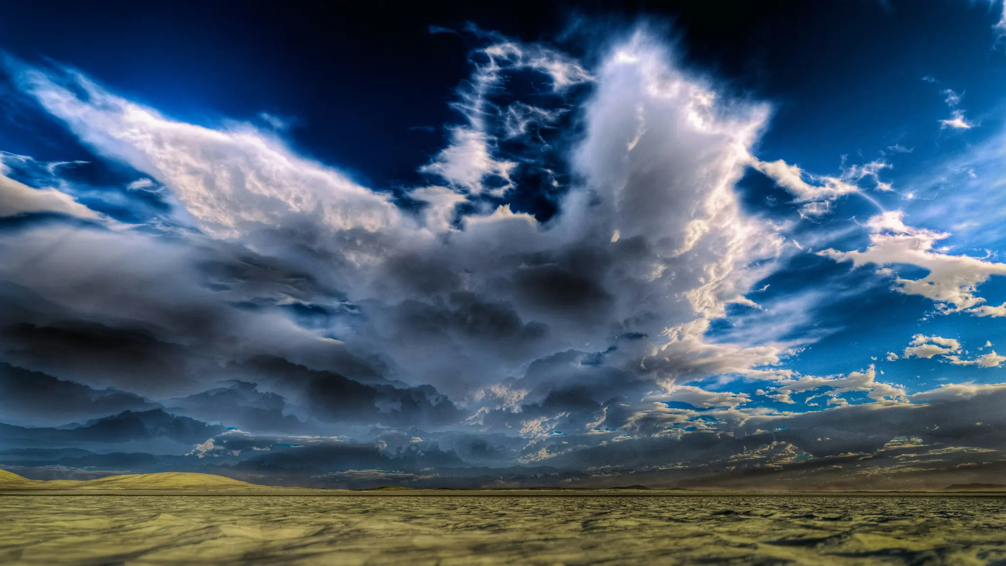 Una vista de gran angular del suelo del desierto con arena texturizada bajo un cielo dramático lleno de nubes oscuras y