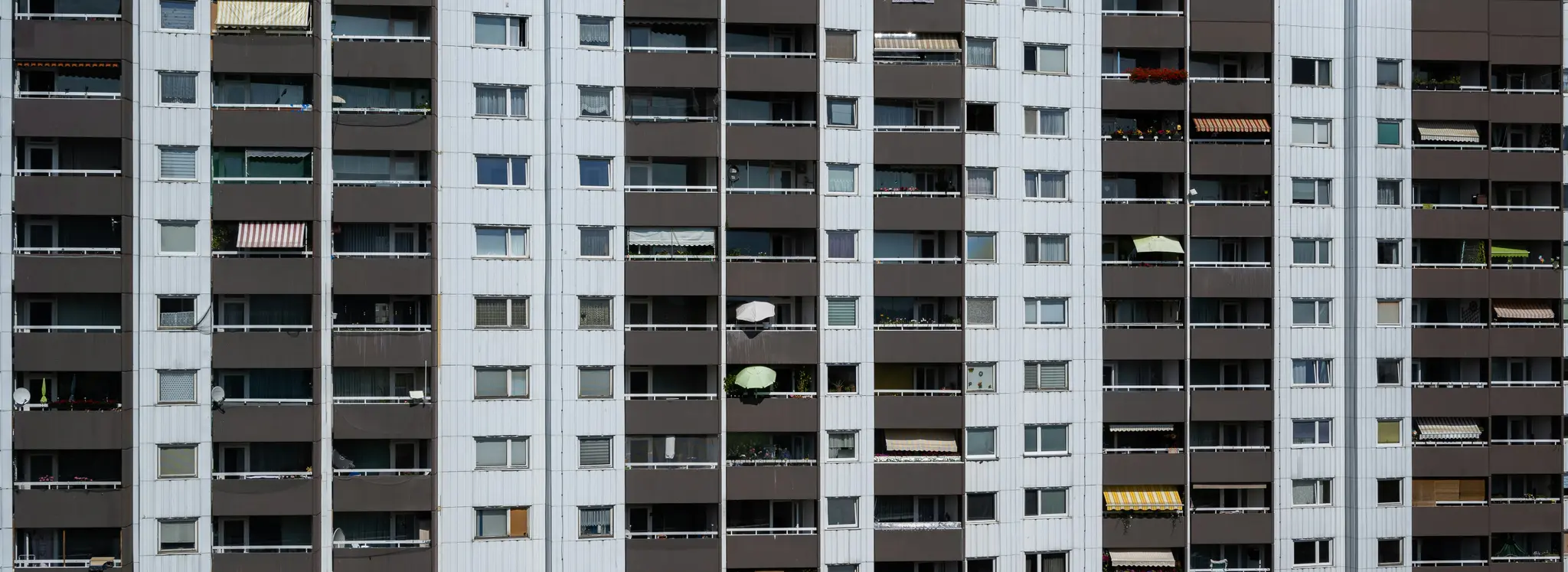 Detailný záber celej fasády vysokého obytného domu s mnohými oknami a balkónmi.