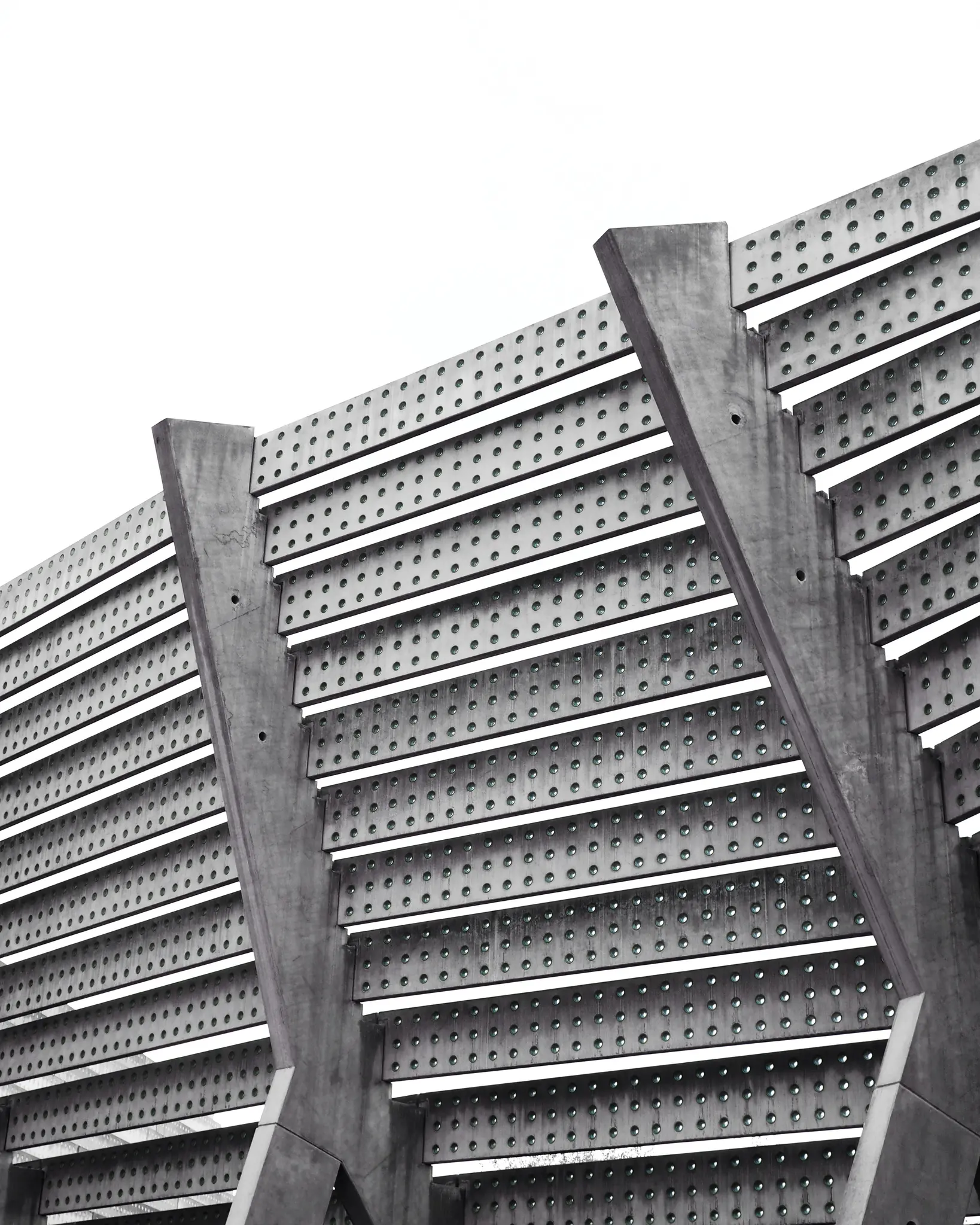 Una foto en blanco y negro, tomada desde un ángulo bajo, de una estructura arquitectónica moderna con paneles perforados
