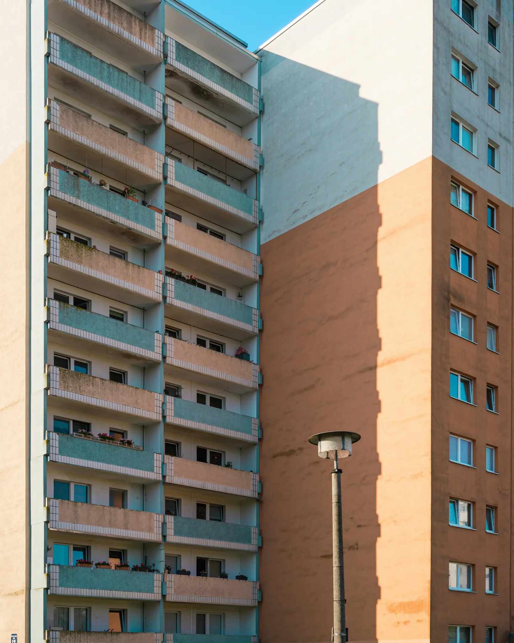 Una toma vertical de dos edificios de apartamentos altos. Uno tiene balcones de color beige y azul claro, el otro es de color