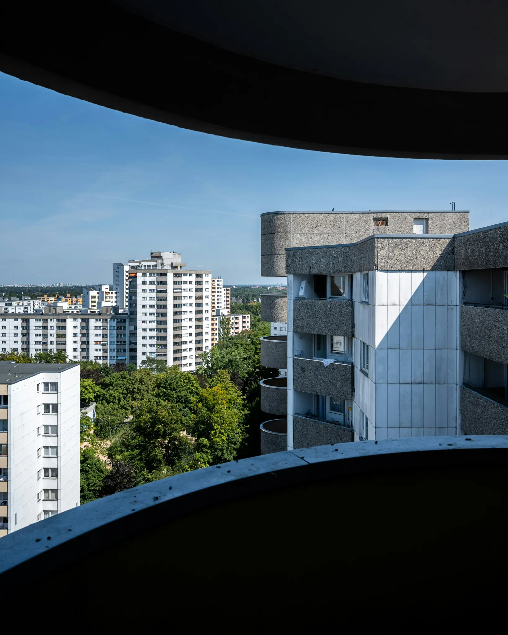 Una vista de ángulo alto desde un balcón oscuro que muestra un paisaje urbano con numerosos edificios de apartamentos de gran