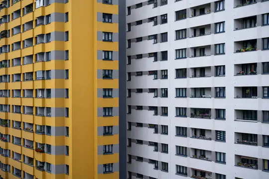Una vista detallada de dos altos edificios de apartamentos. El edificio de la izquierda es amarillo con rayas horizontales