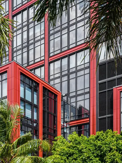 Un edificio moderno con una sorprendente facciata rossa e nera, con numerose grandi finestre, parzialmente incorniciato da