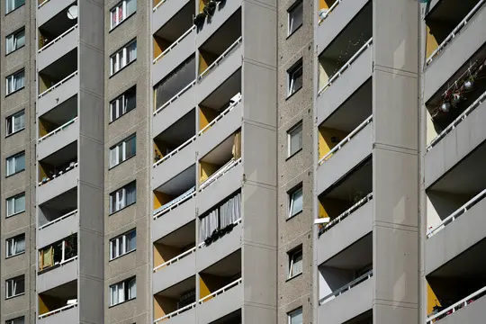 Una vista de primer plano y en ángulo de la fachada de un edificio de apartamentos de hormigón, que muestra varios balcones