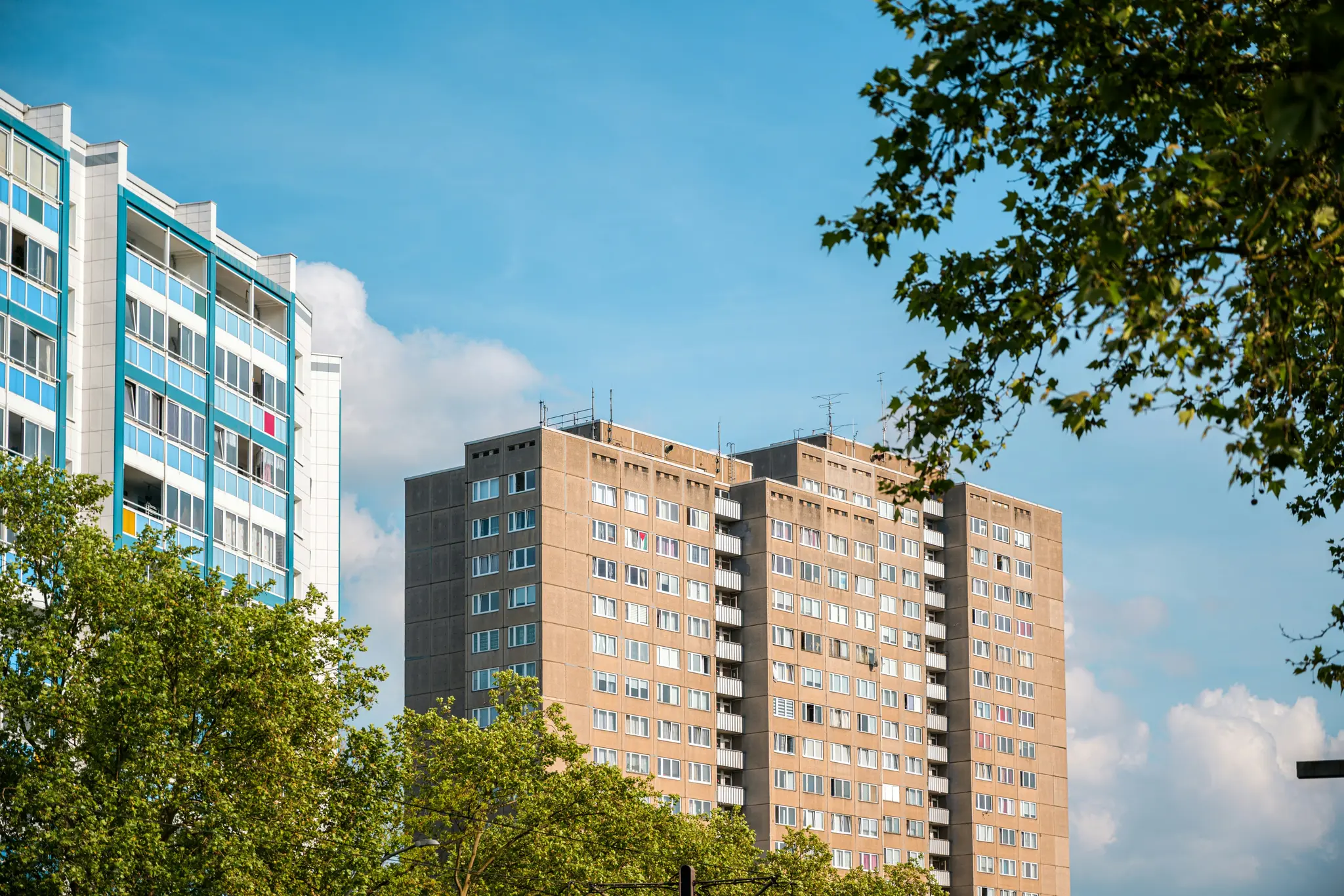 Dos edificios residenciales altos, uno con balcones azules y blancos y otro de hormigón beige, se alzan contra un cielo