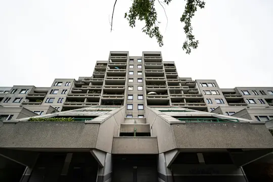 Vista dal basso di un grande edificio di appartamenti brutalista grigio con una facciata a gradoni e a terrazza sotto un