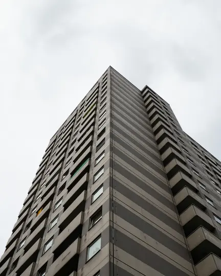 Una ripresa dal basso di un alto edificio grigio con strisce orizzontali grigio scuro, che si protende verso un cielo