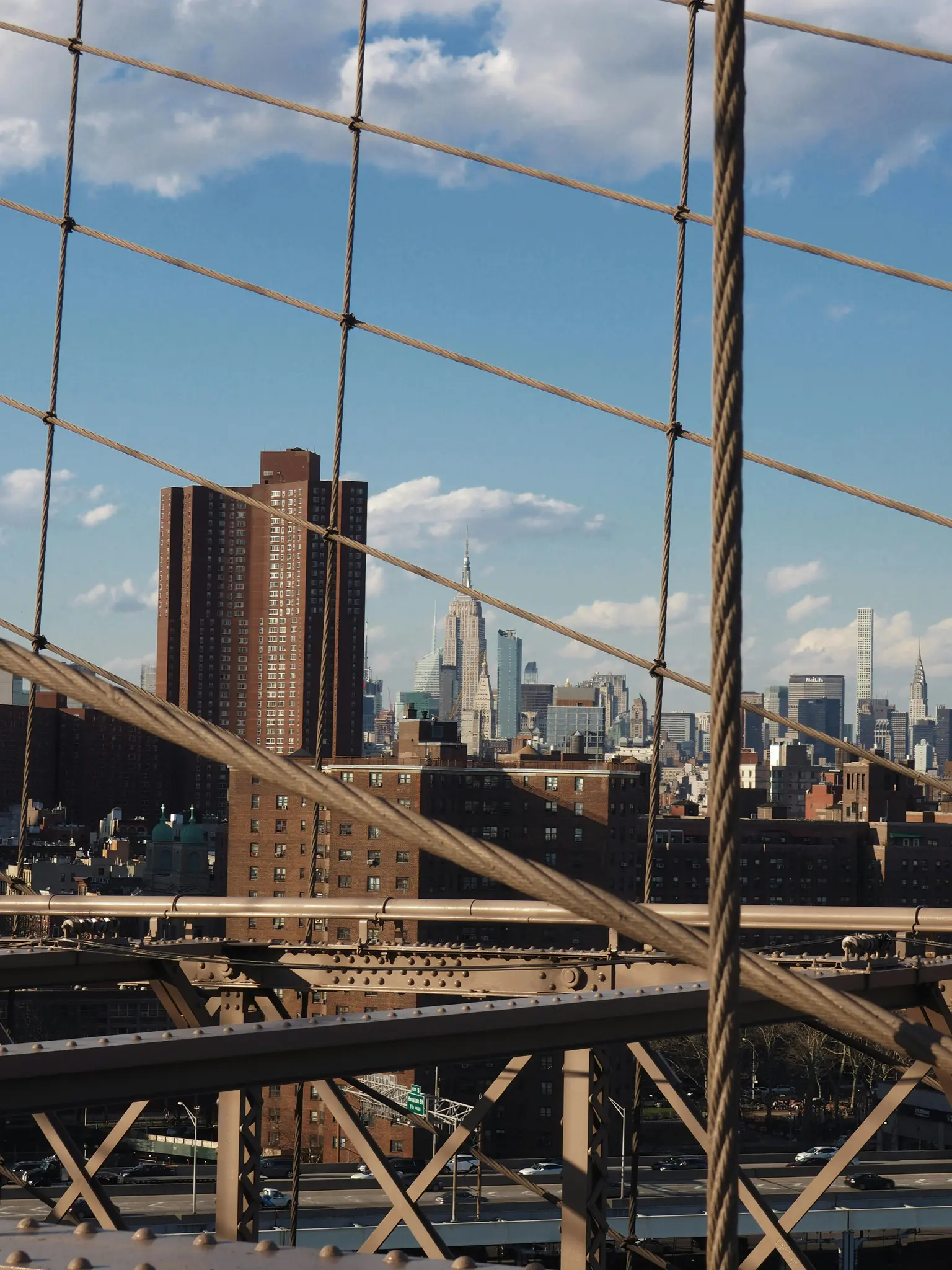 Una vista del horizonte de la ciudad de Nueva York, incluido el Empire State Building, enmarcada por los intrincados cables y