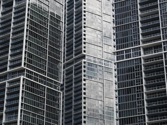 Una vista ravvicinata e astratta di tre moderni grattacieli, con numerose finestre e balconi in una vista monocromatica...