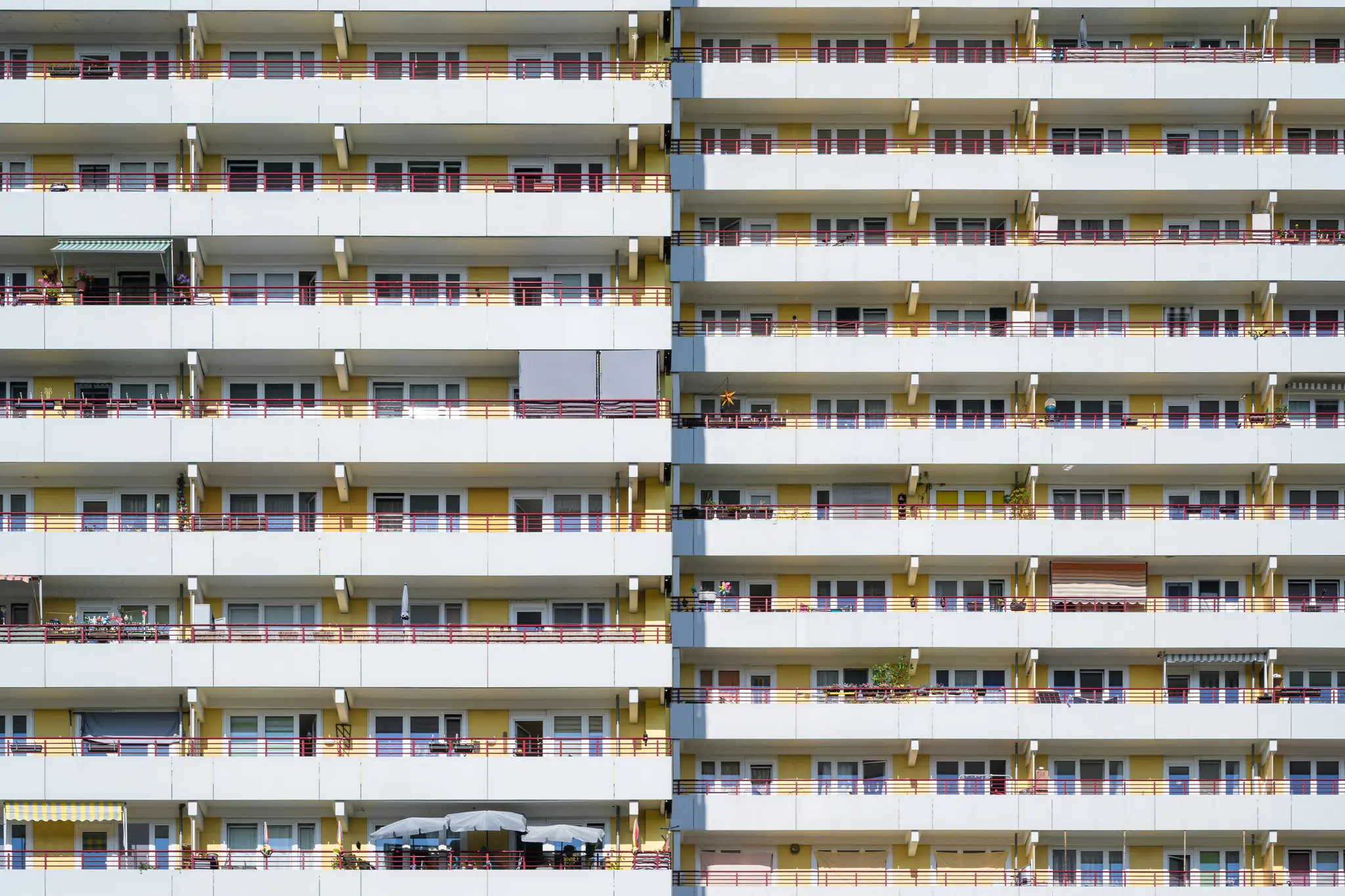 Vista frontal a pantalla completa de la fachada de un edificio de apartamentos de varios pisos, con hileras de balcones