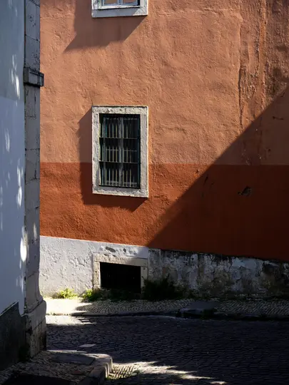 Una facciata di edificio soleggiata con una sezione superiore arancione e una sezione inferiore arancione più scura. Una