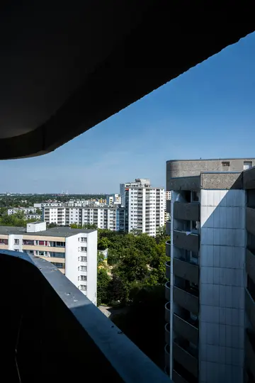 Una vista de pájaro desde un balcón que muestra un paisaje urbano con numerosos edificios residenciales blancos y grises y
