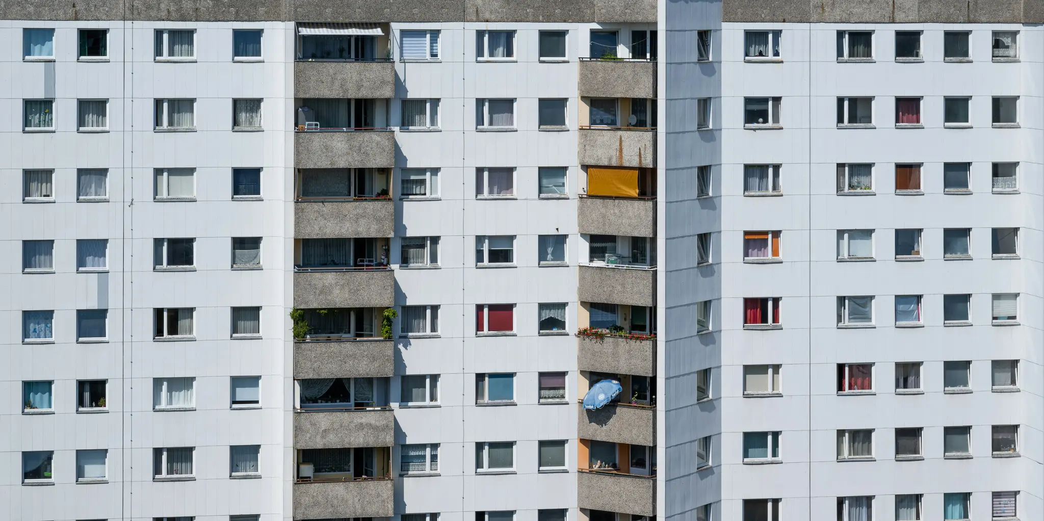 Una vista de primer plano, a pantalla completa, de la fachada de un edificio residencial alto, con numerosas ventanas y