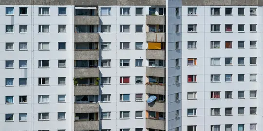 Una vista ravvicinata, a schermo intero, della facciata di un edificio residenziale alto, con numerose finestre e diversi