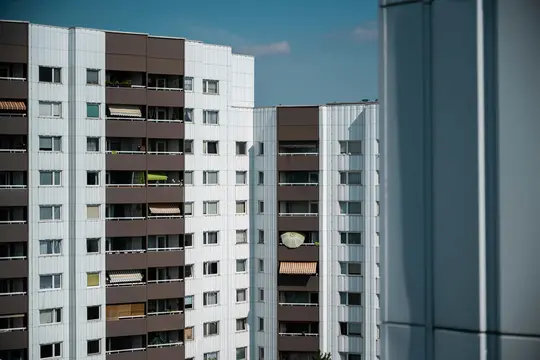 Un alto e moderno edificio di appartamenti con pannelli verticali alternati bianchi e marroni. Numerose finestre e balconi