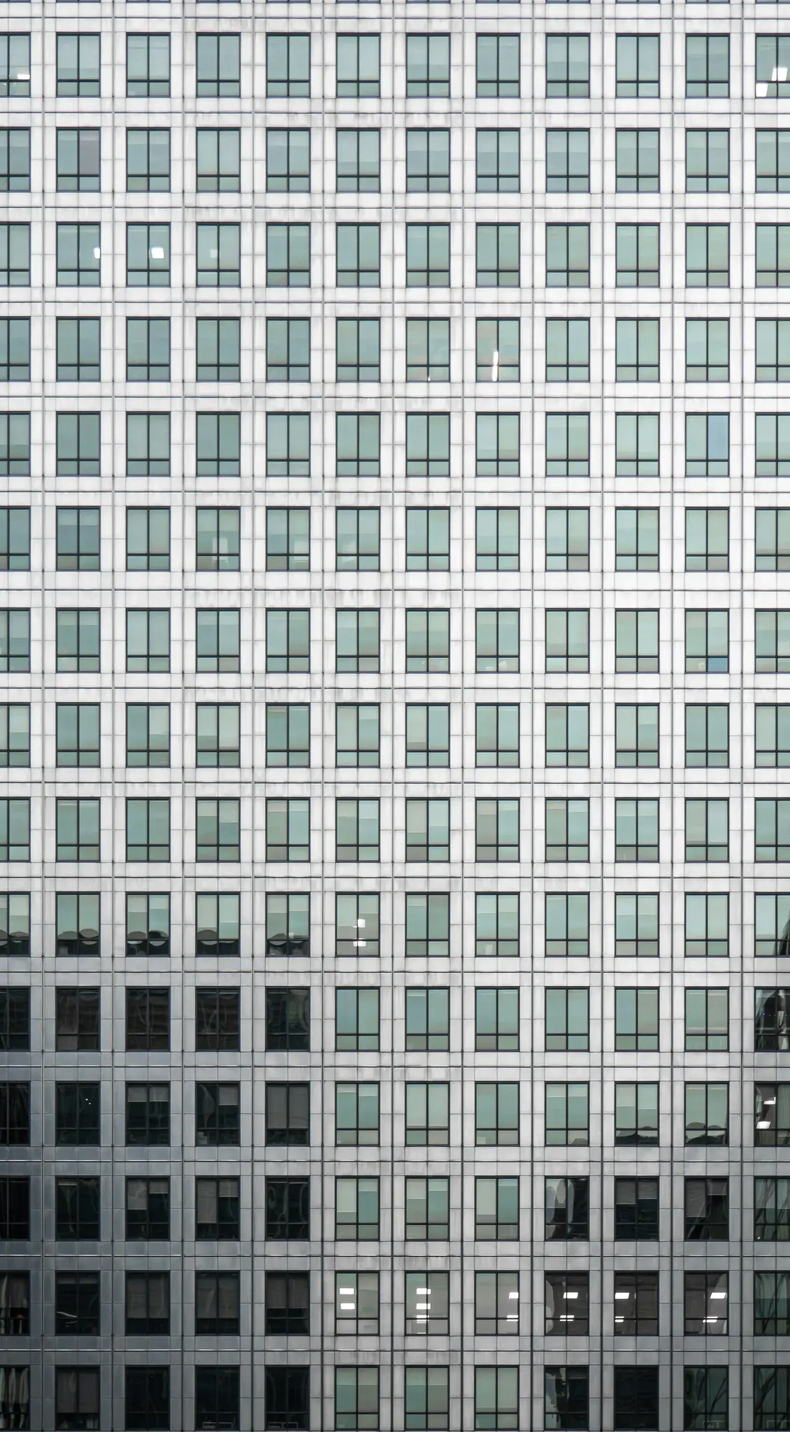 Una toma simétrica de la fachada de un edificio moderno, con un patrón repetitivo de ventanas cuadradas.