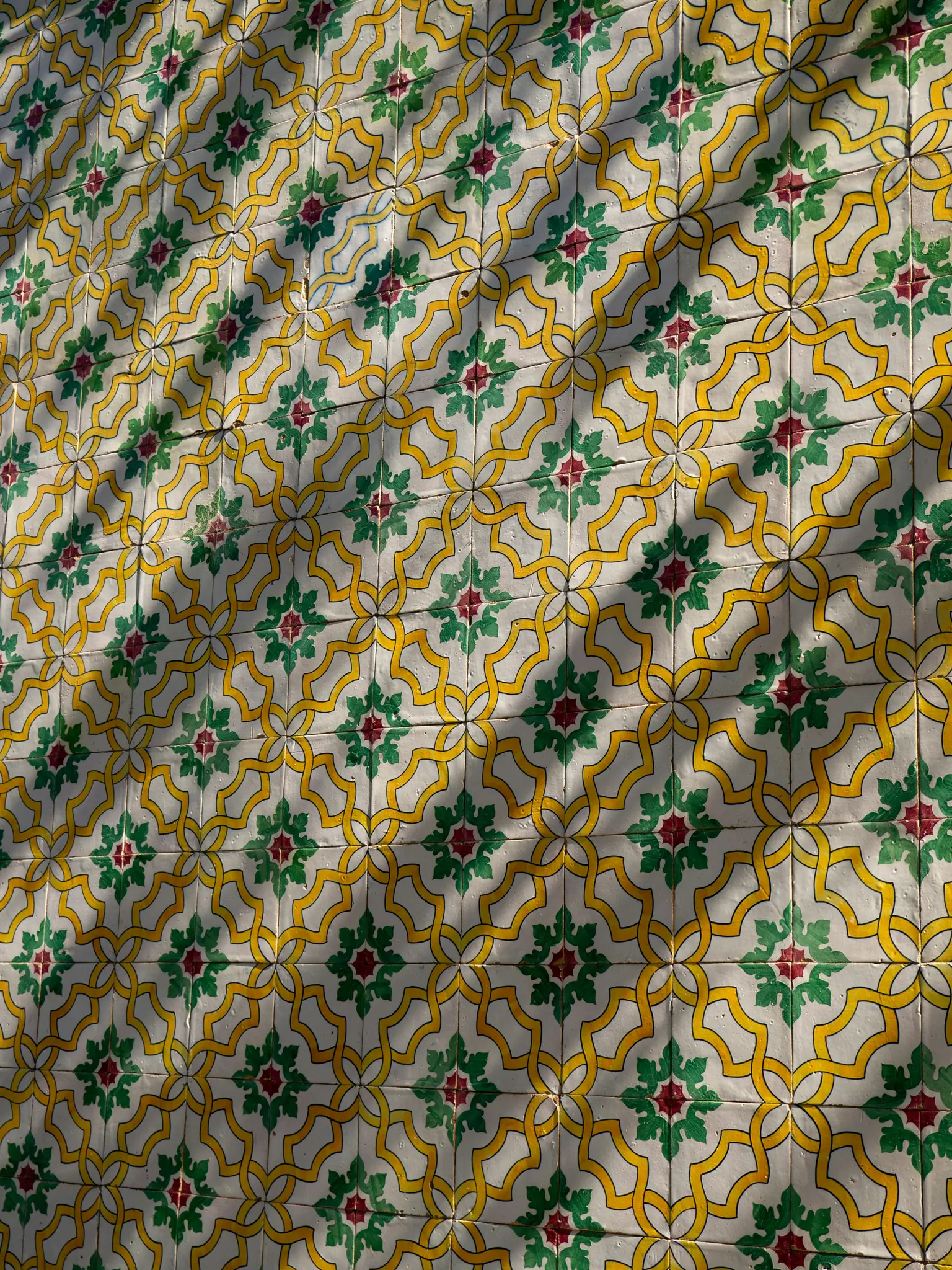 Primer plano de una pared cubierta con azulejos cerámicos blancos. Los azulejos presentan un patrón repetitivo de líneas