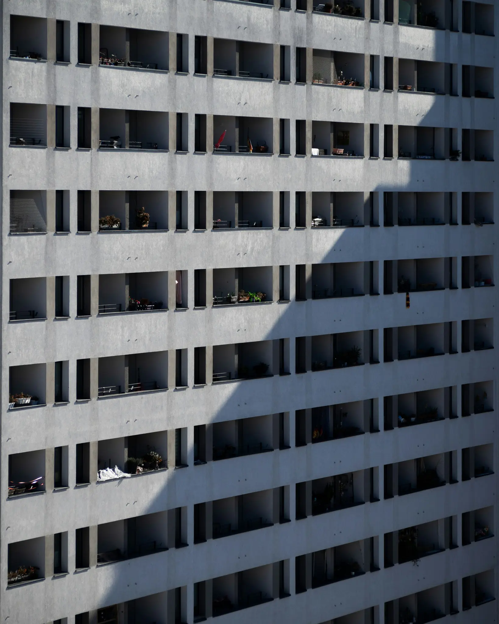 Una vista oblicua y elevada de la fachada de un edificio de apartamentos moderno. Filas de balcones rectangulares proyectan