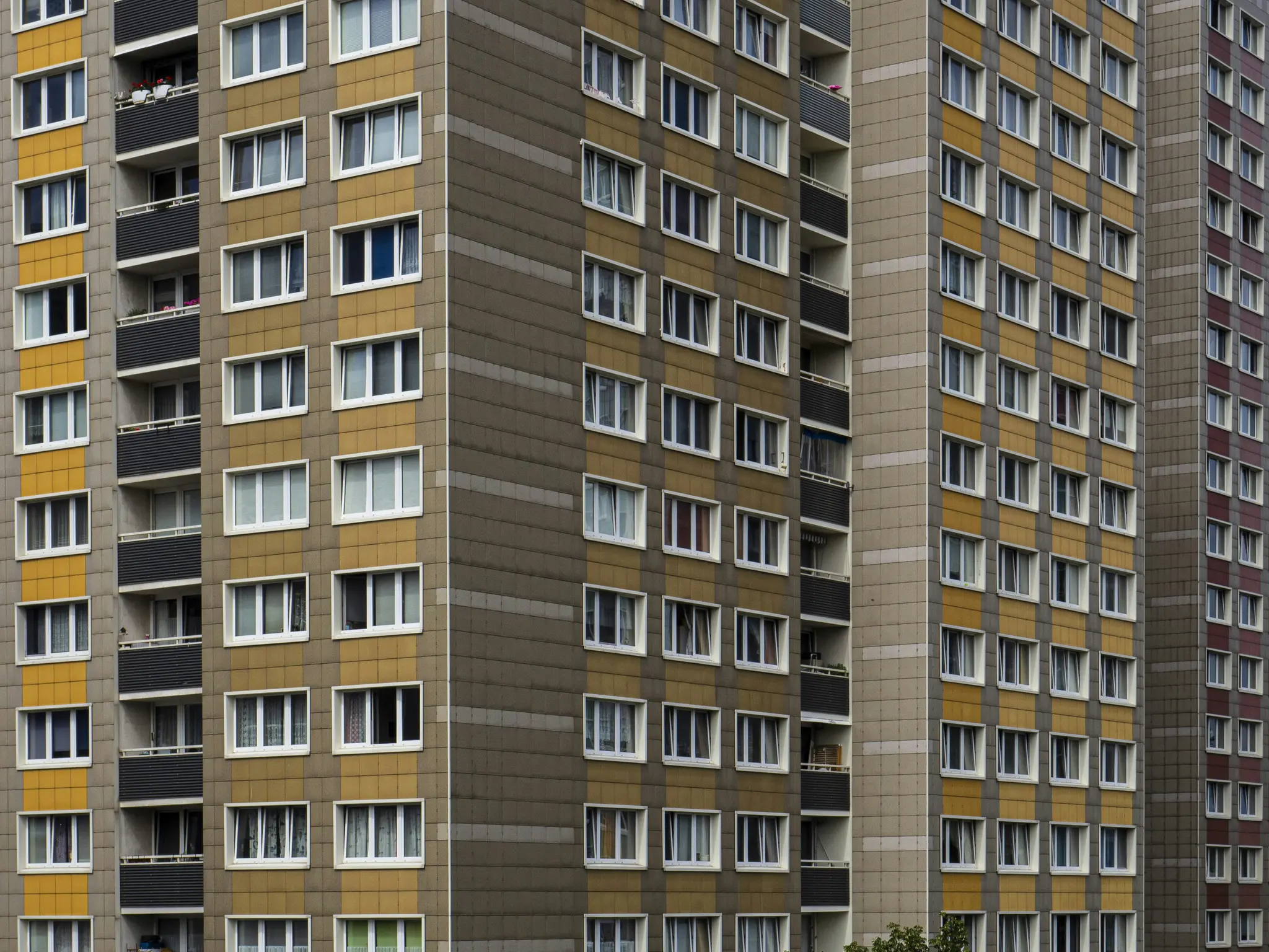 Detailný pohľad na viacero fasád bytových domov. Budovy majú rady okien a balkónov.