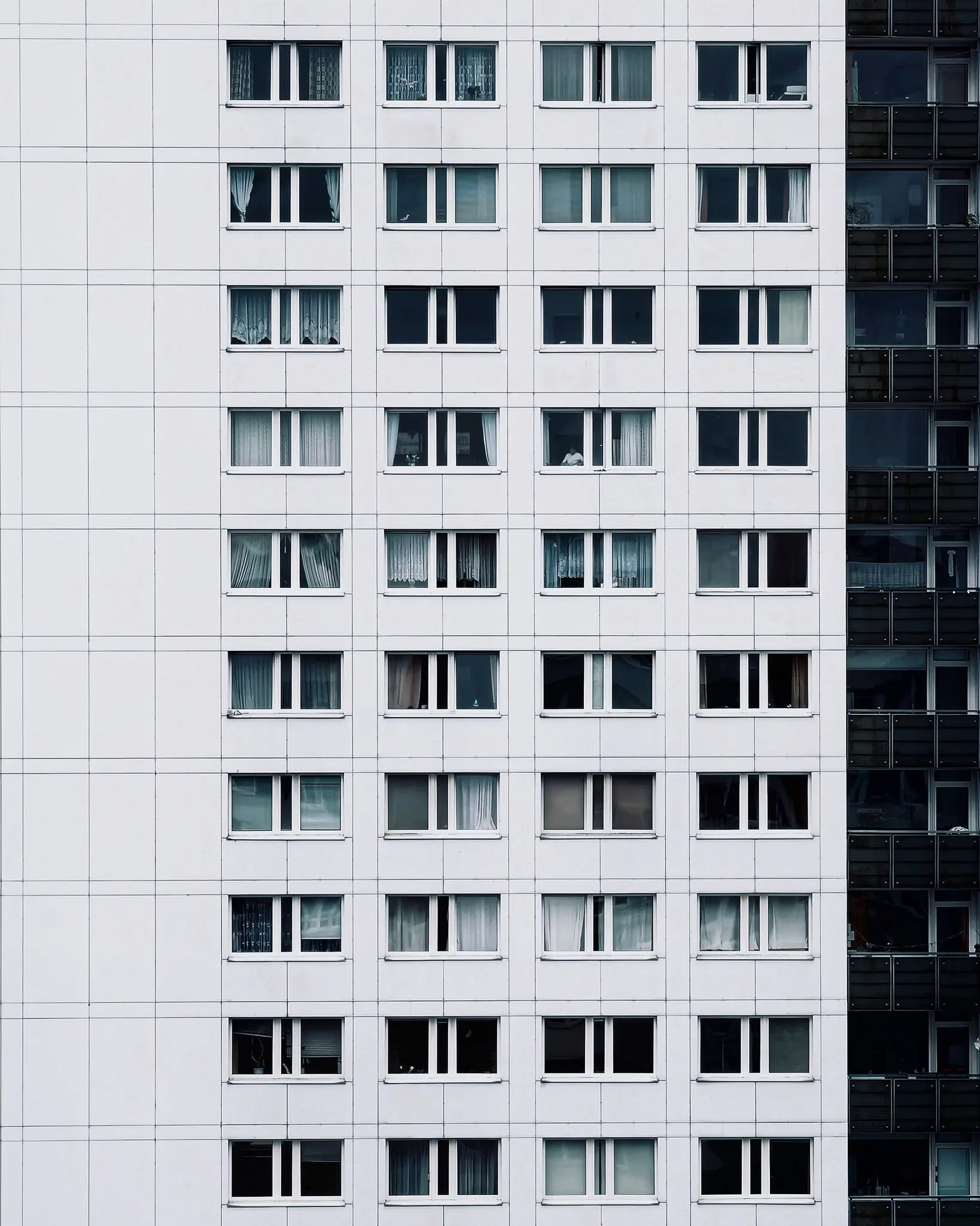Una vista de primer plano, de frente, de la fachada de un edificio alto, con muchas hileras de ventanas rectangulares con