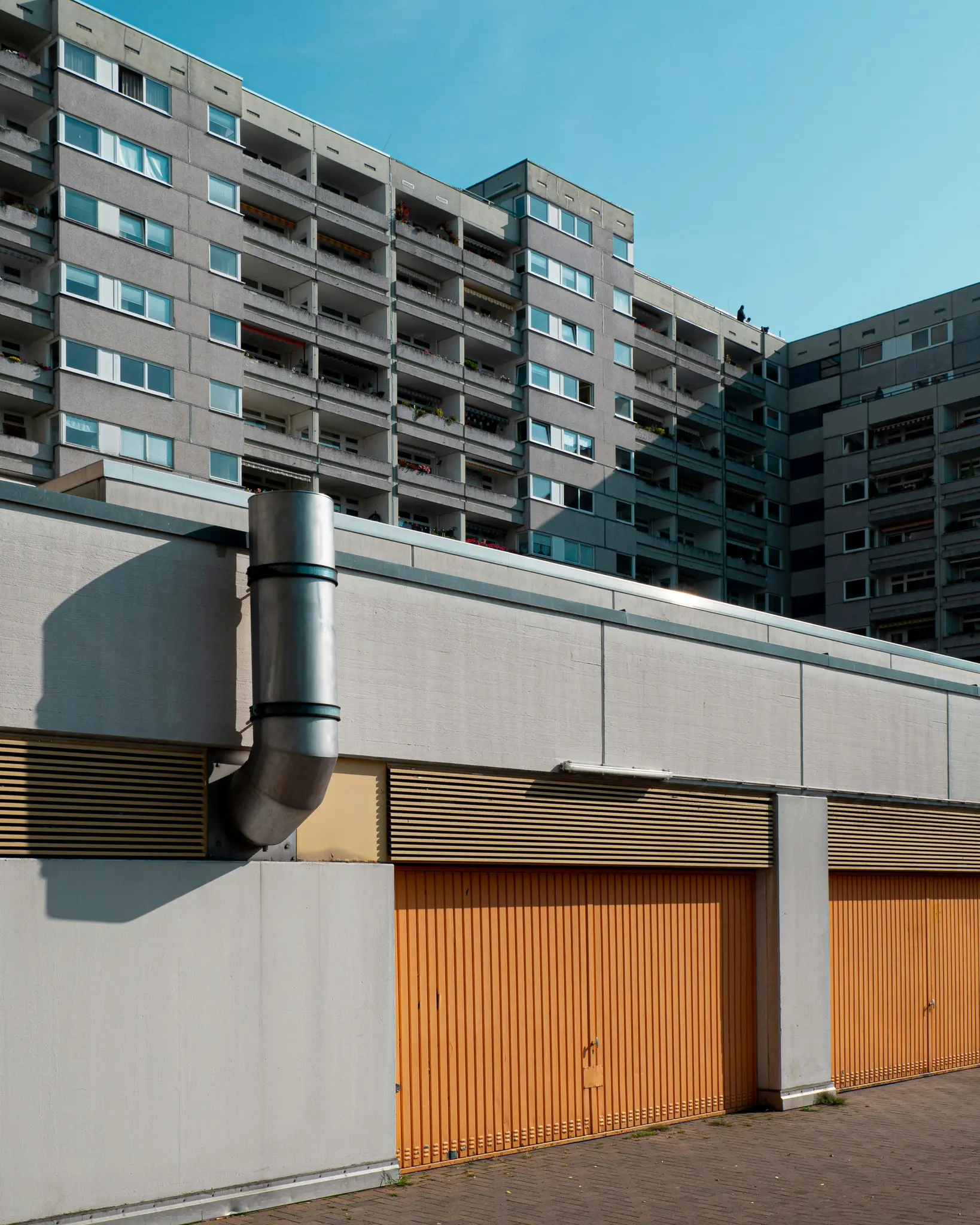 Una foto de ángulo bajo de un edificio de apartamentos grande y gris de hormigón con muchas ventanas y balcones bajo un cielo