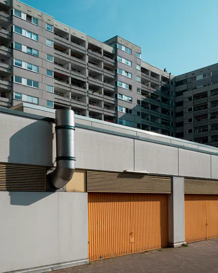 Foto in prospettiva dal basso di un grande edificio di appartamenti in cemento grigio con molte finestre e balconi sotto un