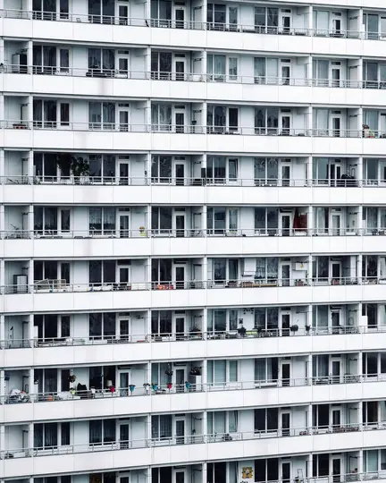 Uno scatto dettagliato a tutto schermo della grande facciata bianca di un condominio con molti balconi e finestre.