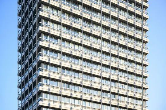 Una vista ravvicinata e leggermente angolata della facciata di un moderno grattacielo, con numerose finestre e balconi.