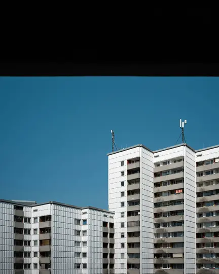 Ein klares Bild mehrerer weißer und grauer Wohngebäude unter einem klaren blauen Himmel, mit einem dunklen horizontalen