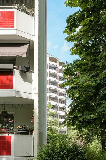 Uno scatto verticale mostra l'angolo di un edificio residenziale bianco con sezioni di tetto in tegole rosse a sinistra e uno