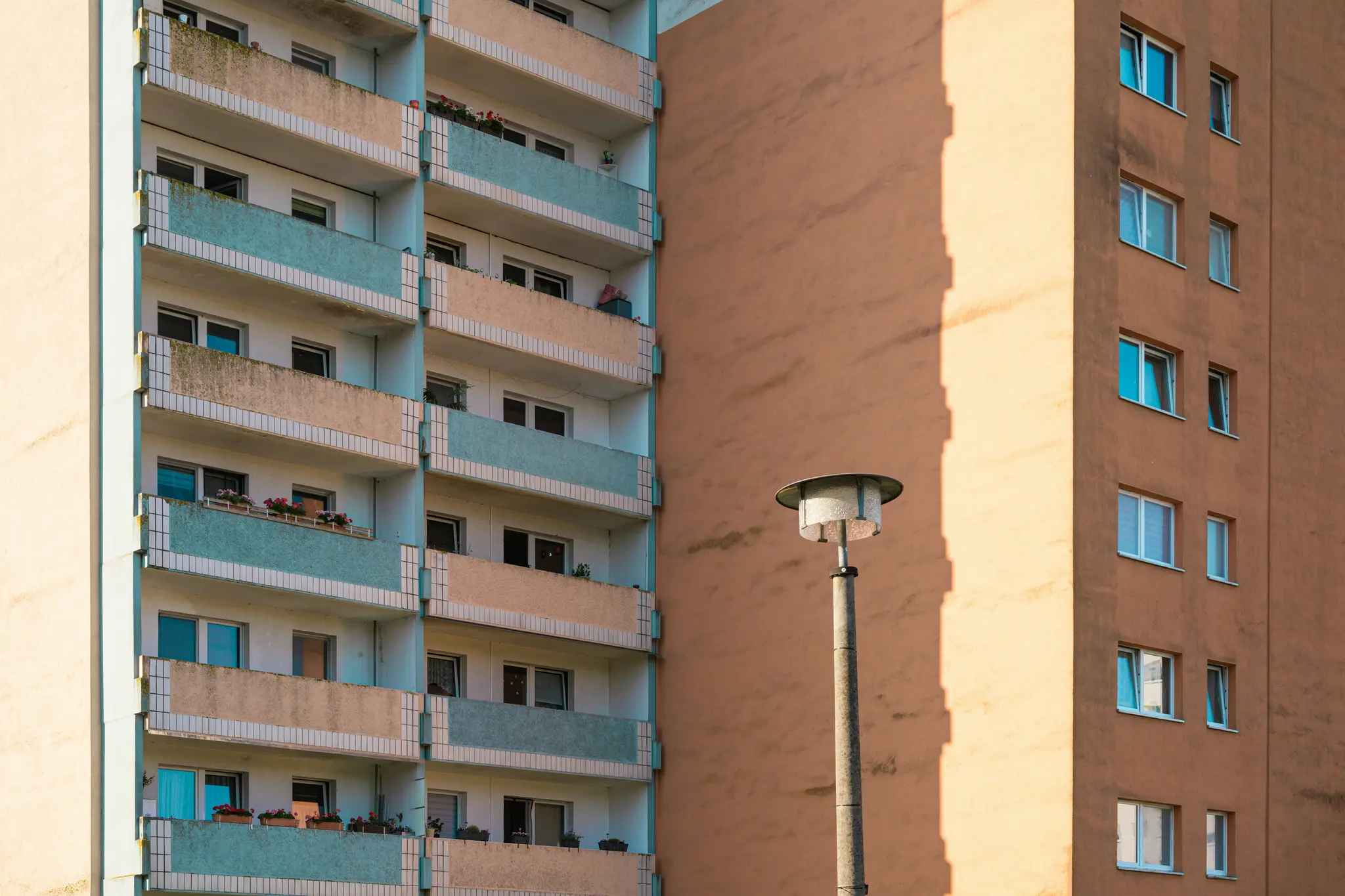 Gros plan de deux immeubles d'habitation. Le bâtiment de gauche a des balcons avec des garde-corps bleu clair et beige. Le