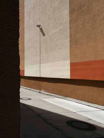 Un vicolo stretto con un muro di edificio alto e multicolore sulla destra e un muro scuro sulla sinistra. È visibile una