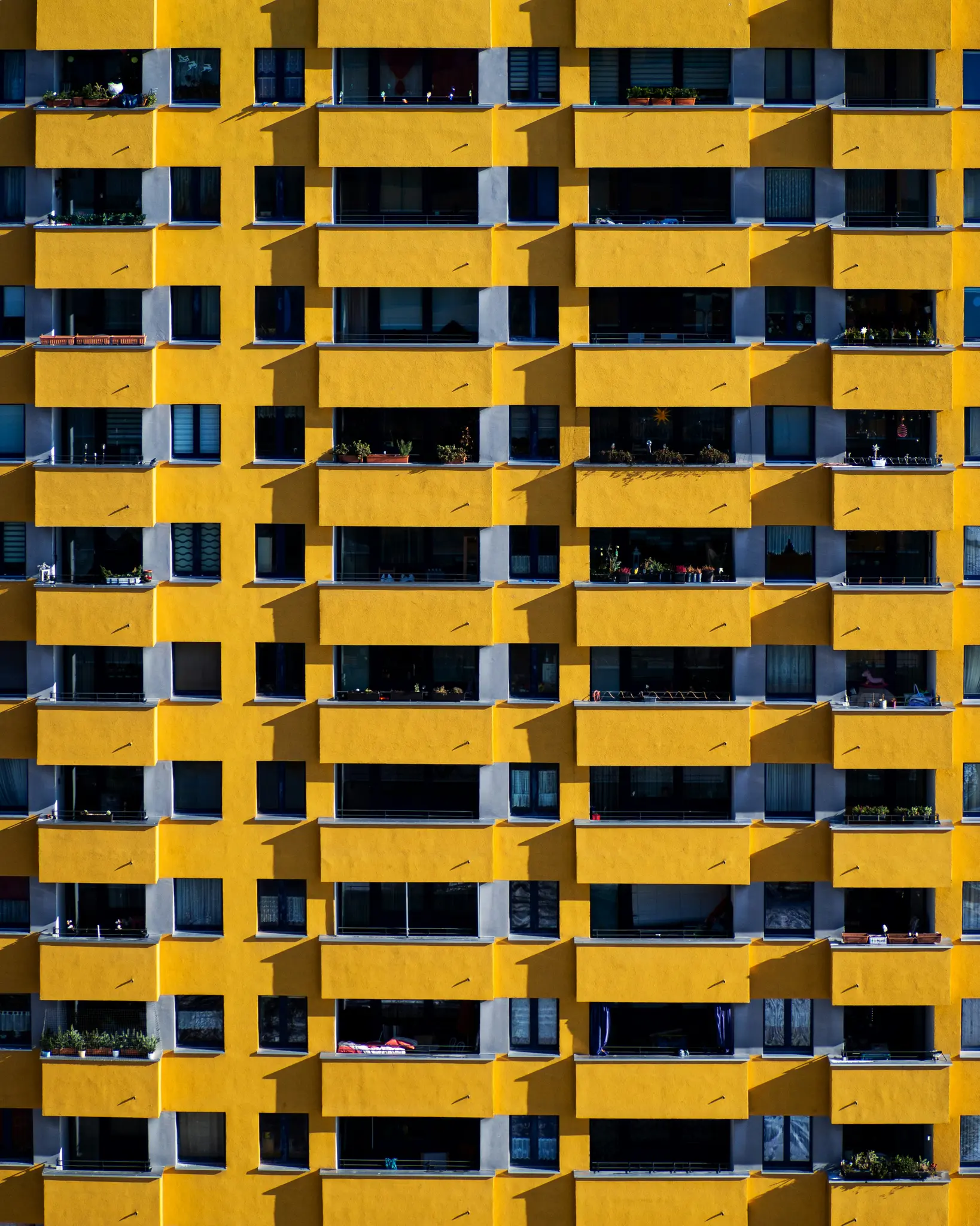 Vista de fotograma completo, de frente, de la fachada de un edificio de apartamentos moderno, con paredes de color amarillo