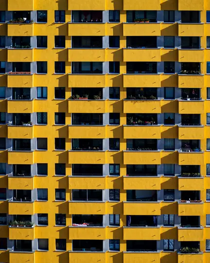 Vista de fotograma completo, de frente, de la fachada de un edificio de apartamentos moderno, con paredes de color amarillo