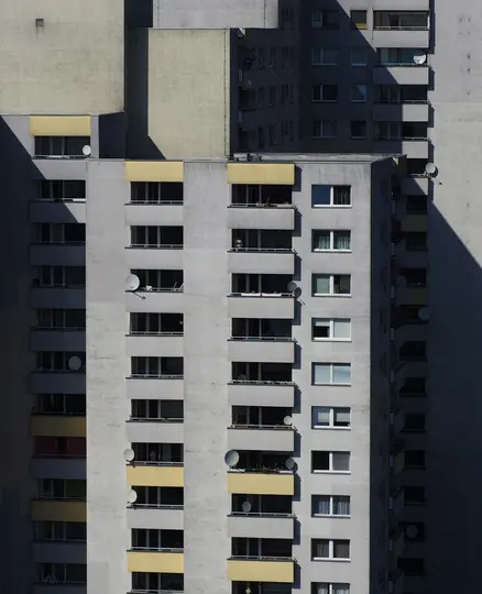 Una vista ravvicinata e astratta della facciata di un condominio grigio. Tende da sole e balconi gialli creano un motivo